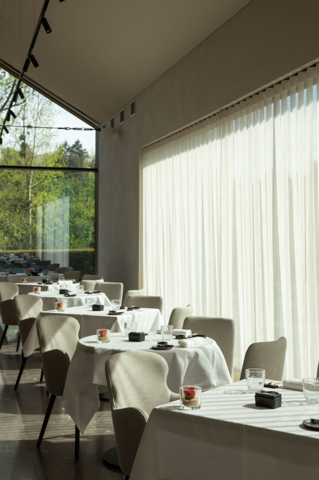 Tül perdeli restoranda beyaz masa örtülü masalar